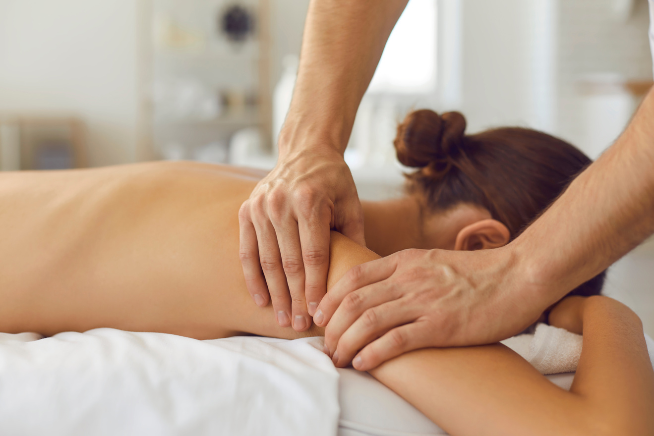 Woman Lying on Massage Table Enjoying Delicate Body Massage in Health Clinic or Luxury Spa Salon