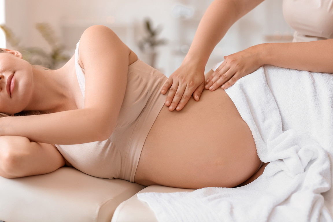 Young Pregnant Woman Having Massage in Spa Salon